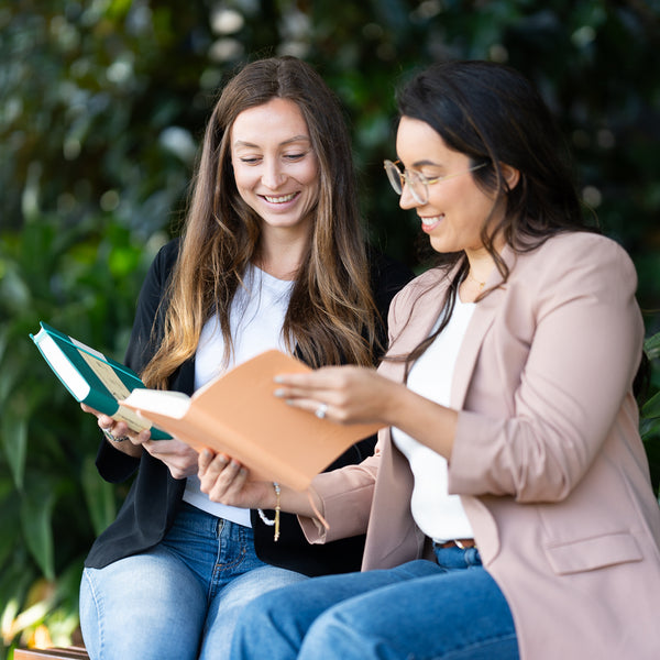 Two women reading the 2027 Mental Fitness Diary to improve their mental health.