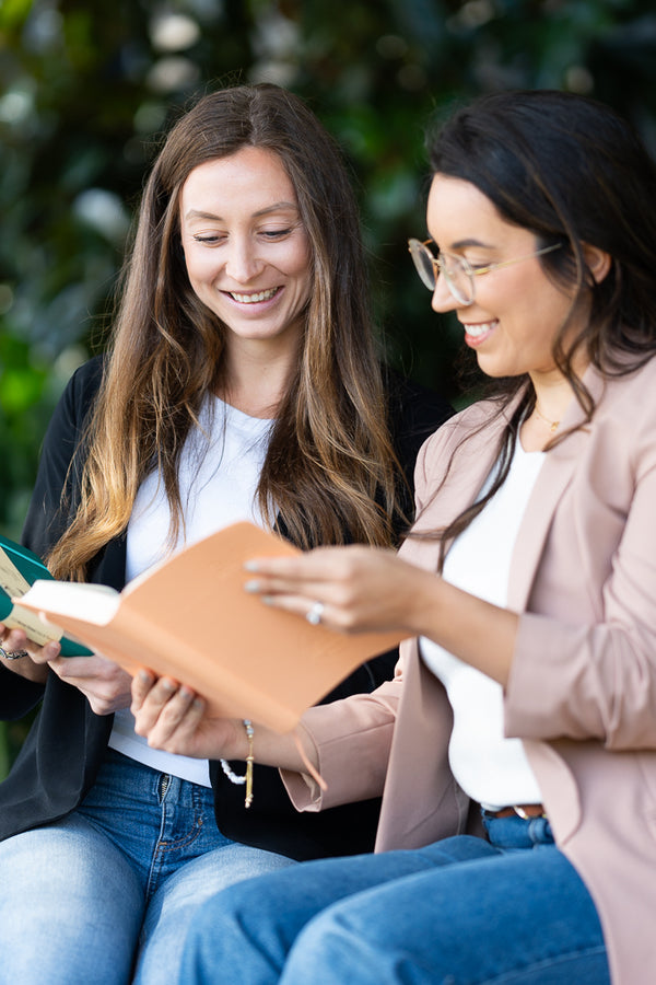 Two women reading the 2027 Mental Fitness Diary to improve their mental health.