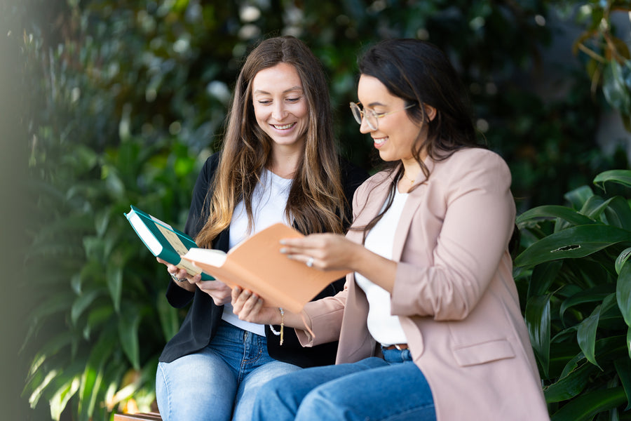 Two women reading the 2027 Mental Fitness Diary to improve their mental health.